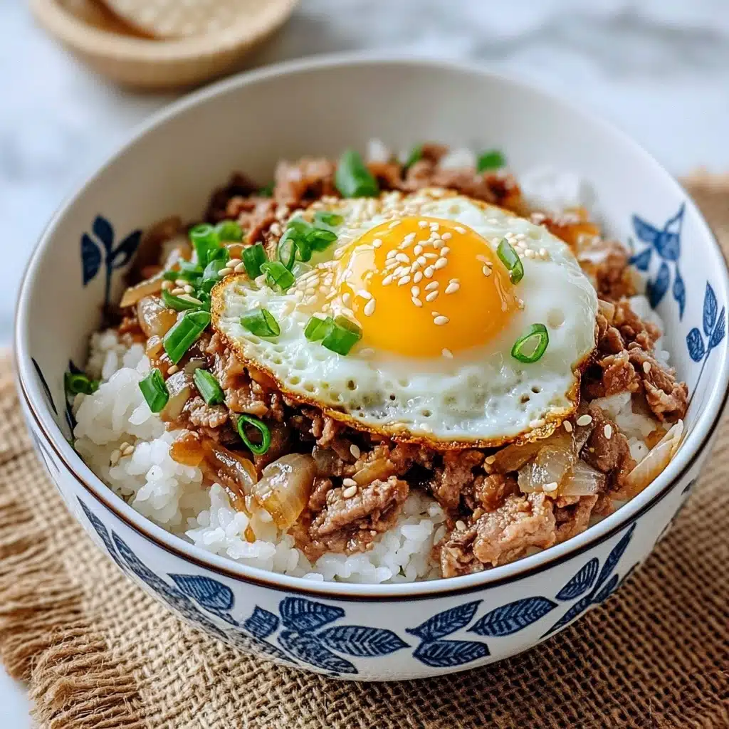 Gyudon Japanese Beef & Rice Bowl, Japanese Gyudon recipe, Easy Gyudon bowl, Authentic Japanese beef rice dish, Japanese comfort food A white bowl with blue leaf patterns holds a dish with three layers: a bottom layer of white steamed rice with a soft, fluffy texture, a middle layer of cooked brownish meat mixed with translucent, cooked onions, and a top layer featuring a bright yellow fried egg yolk surrounded by a white cooked egg white sprinkled with sesame seeds and chopped green onions; the bowl is placed on a textured brown surface with chopsticks and a fork beside it, and the background is a white marbled texture.