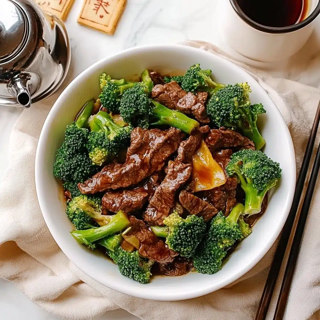 Beef and Broccoli Stir-Fry, homemade Beef and Broccoli, easy Asian stir-fry, quick weeknight dinner, healthy beef stir-fry A white bowl filled with a dish of bright green broccoli florets and multiple pieces of brown meat coated in a shiny sauce, the broccoli adds a textured, vibrant layer around and under the meat. The bowl sits on a rough, beige cloth with a soft focus on a silver teapot and a small cup in the background, all set on a white marbled surface. The meat slices are spread evenly through the broccoli, creating a balanced and colorful mix.