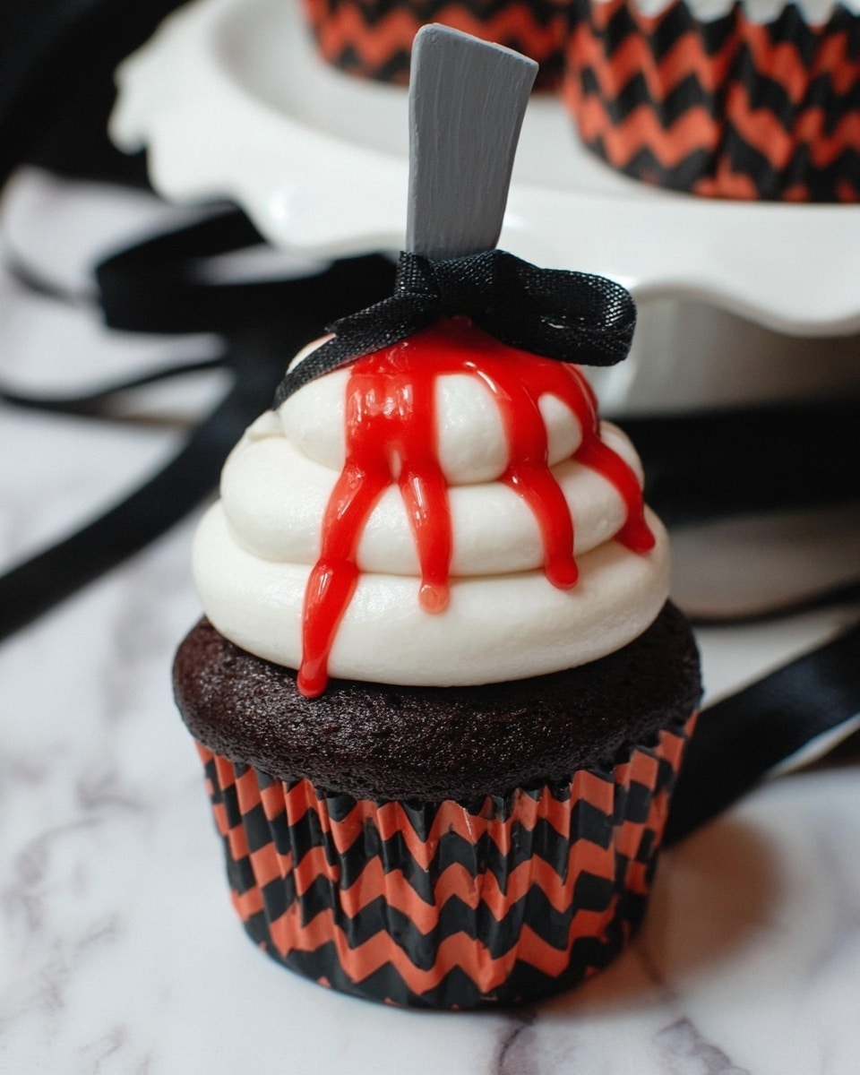 A dark chocolate cupcake sits in a black and orange zigzag patterned paper liner on a white marbled surface. It has three thick, smooth layers of white frosting stacked on top in a swirl shape. Bright red sauce drips over the top layer of frosting, with four thick drops flowing downwards. A small gray plastic cleaver with a black handle is stuck into the top of the frosting, with a black ribbon tied around its handle. The background shows a white plate with black ribbons around its edges. Photo taken with an iphone --ar 4:5 --v 7