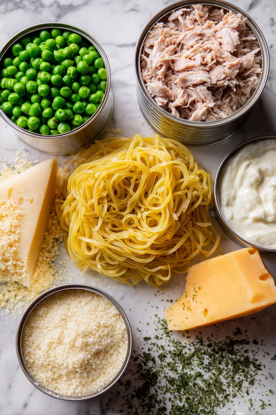 Flat lay of fresh yellow egg noodles coiled loosely, two shiny silver cans of tuna opened showing flaky light pink tuna, a small pile of bright green frozen peas glistening with frost, a wedge of sharp orange cheddar cheese with a slightly crumbly texture, a mound of creamy sour cream with a smooth surface, a handful of golden brown panko breadcrumbs with a rough texture, a small heap of pale beige grated parmesan cheese, and scattered dried parsley flakes in vibrant green, all arranged artfully to highlight their natural colors and textures, placed on white marbled surface, photo taken with an iphone --ar 2:3 --v 7 - Creamy Tuna Noodle Casserole, easy tuna casserole, comforting family dinner, quick weeknight dinner, tuna pasta bake