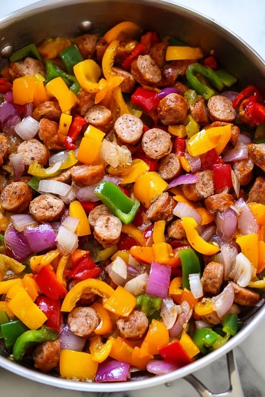 The image shows a pan filled with cooked sausage slices and mixed vegetables. There are three clear layers: the first layer is round sausage pieces that are browned and cooked, scattered evenly throughout the pan. The second layer consists of diced bell peppers in three colors—yellow, red, and green—each piece vibrant and slightly softened from cooking. The third layer includes chopped onions that are translucent with hints of light purple and white, mixed closely with the peppers and sausage. The pan itself is shiny metal on a white marbled texture surface. photo taken with an iphone --ar 2:3 --v 7 - Lightning-Fast Cheesy Three-Pepper Ravioli with Italian Sausage, quick and easy ravioli dinner, colorful Italian sausage skillet, 20-minute pasta recipe, savory pepper pasta