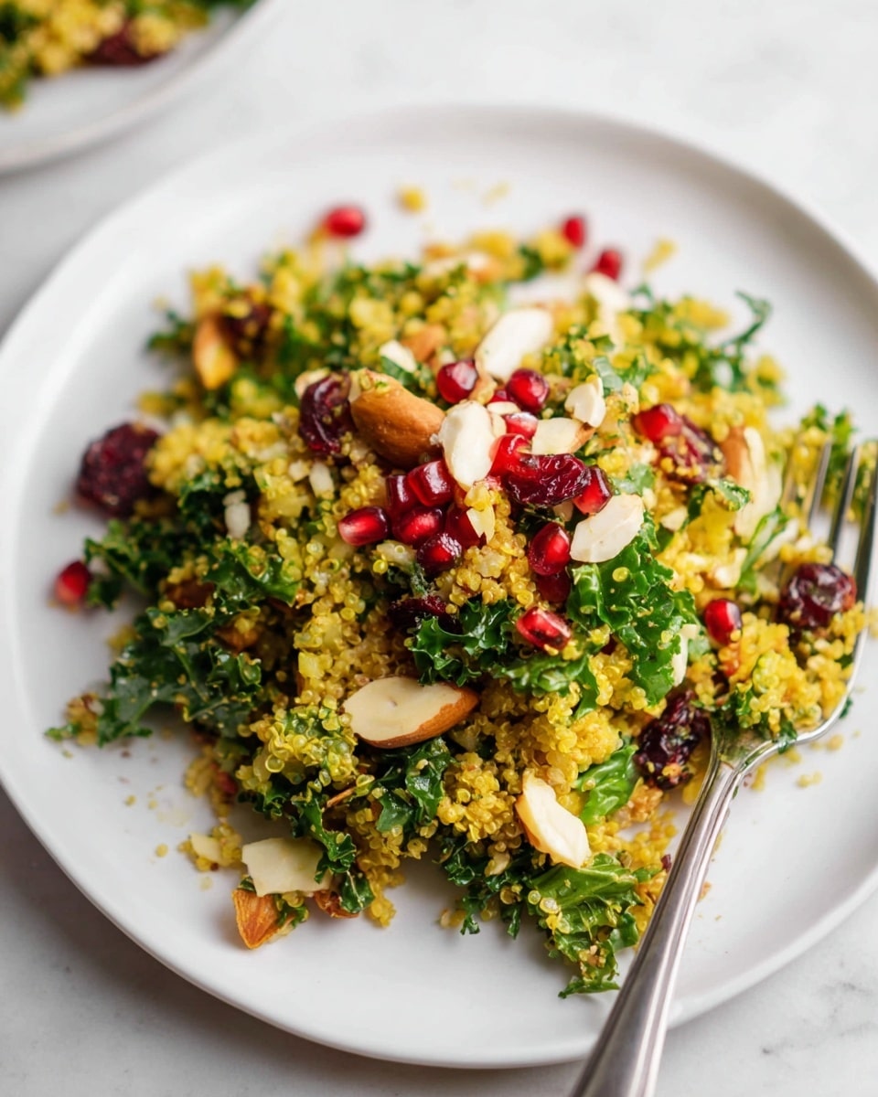 The dish shows a colorful quinoa salad on a white plate, placed on a white marbled surface. The salad has three main layers: the bottom layer is bright yellow quinoa, mixed with greens like kale which add a mix of dark and light green textures. Scattered throughout are small pieces of white nuts and dark dried cranberries, adding contrast. On top are bright red pomegranate seeds that pop with color. A silver fork rests on the right side of the plate, with some salad on it, ready to eat. Photo taken with an iphone --ar 4:5 --v 7