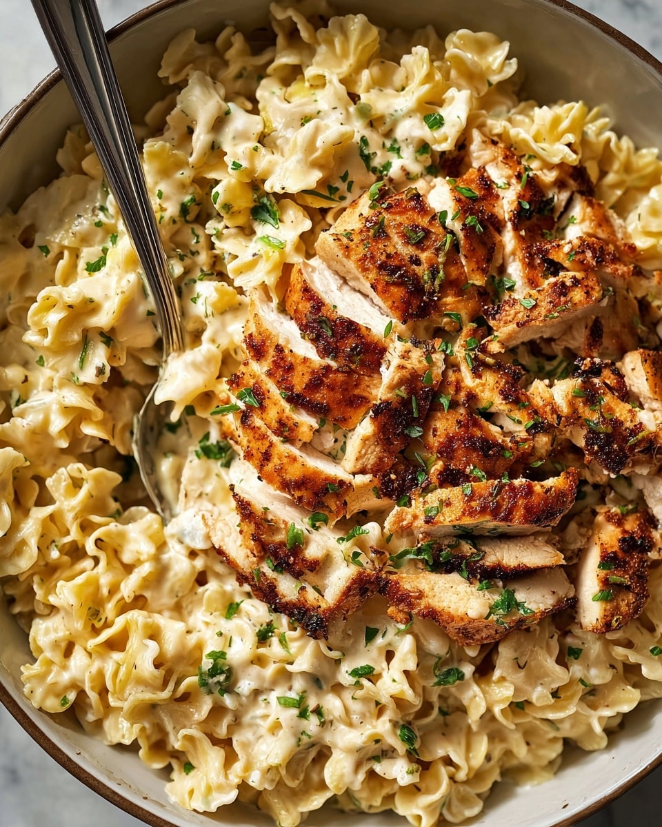 A close-up view of a large white bowl filled with a creamy pasta dish. The bottom layer is made of short, wavy-edged pasta pieces coated in a smooth, pale yellow sauce. Sitting atop the pasta is a generous layer of sliced cooked chicken pieces, golden brown with slightly crispy edges, showing juicy white inside. The chicken and pasta are sprinkled with finely chopped green herbs, adding small pops of color. Two silver spoons are partially buried in the dish, one centered and the other near the bottom right. The whole scene is set against a white marbled surface. photo taken with an iphone --ar 4:5 --v 7