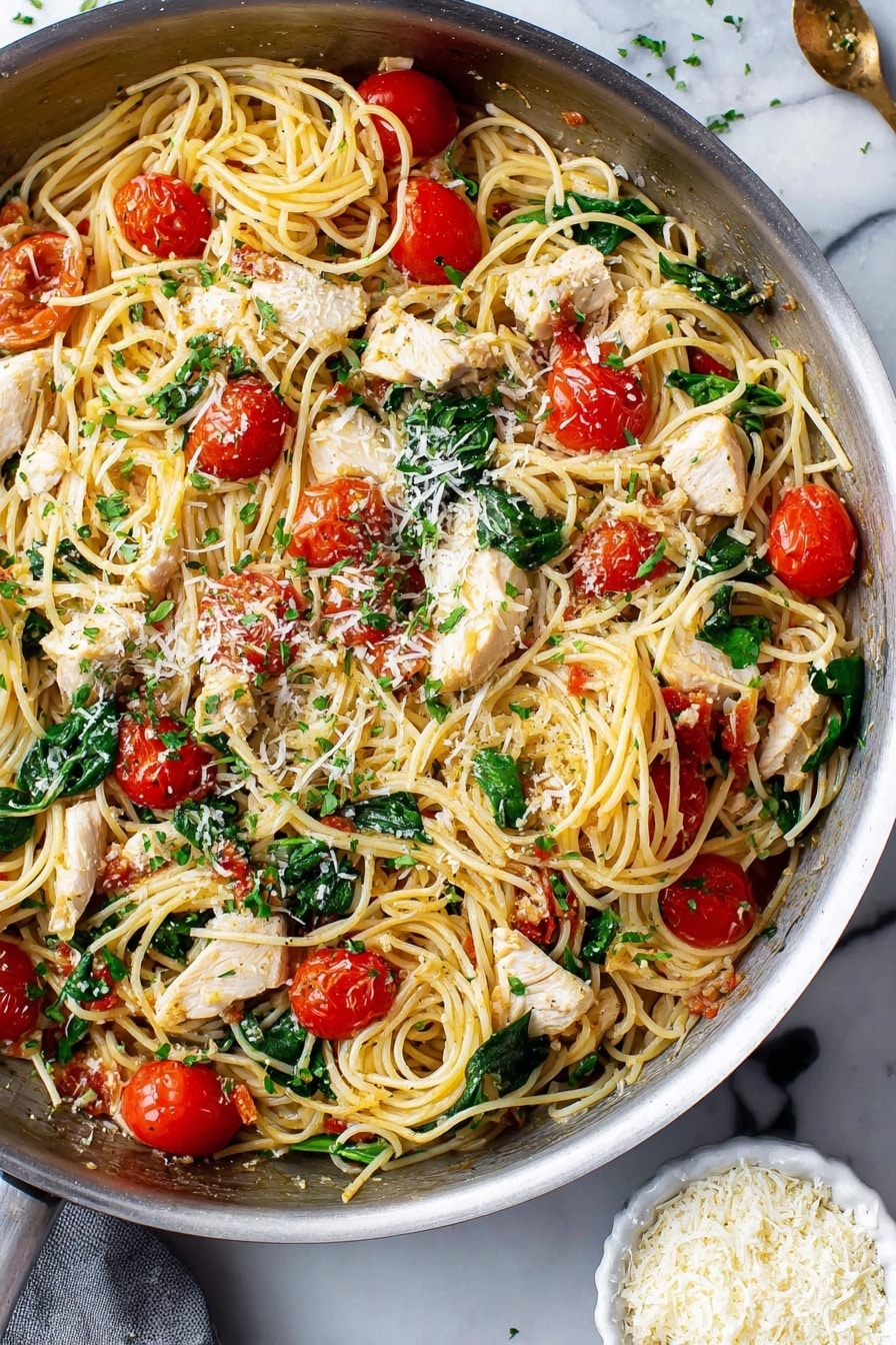 This image shows a pan filled with cooked thin spaghetti mixed with white chicken pieces, bright red cherry tomatoes cut in halves, and fresh green spinach leaves scattered throughout. The pasta looks soft and tangled, and there are small sprinkles of grated cheese and finely chopped green herbs on top. The pan sits on a white marbled surface, and near the bottom right corner, there is a small white bowl filled with more grated cheese. The whole dish looks fresh and colorful. photo taken with an iphone --ar 2:3 --v 7 - Creamy Chicken Scampi with Angel Hair Pasta and Cherry Tomatoes, chicken scampi with angel hair pasta, easy chicken pasta dinner, flavorful chicken pasta recipe, quick creamy chicken pasta