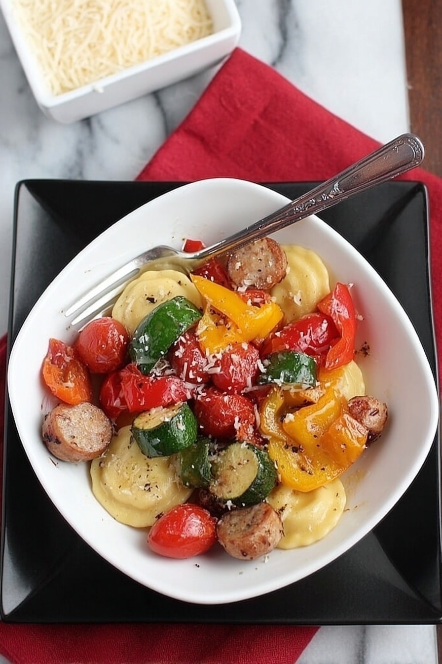 A white square bowl filled with a colorful mix of food sits on a larger black square plate, all placed on a white marbled surface with a red cloth napkin nearby. The bowl contains three round ravioli pieces at the bottom, light yellow in color with a smooth texture. On top of the ravioli are several pieces of sausage, sliced into thick rounds with a browned outer surface, along with large pieces of bell peppers in green, yellow, and red, each showing a slightly glossy and roasted texture. Scattered throughout are bright red cherry tomatoes, some whole, others split, and all glistening slightly. A silver fork rests inside the bowl, angled and leaning toward the right side. Nearby, a white square dish filled with grated cheese is partially visible. The photo taken with an iphone --ar 2:3 --v 7 - Lightning-Fast Cheesy Three-Pepper Ravioli with Italian Sausage, quick and easy ravioli dinner, colorful Italian sausage skillet, 20-minute pasta recipe, savory pepper pasta