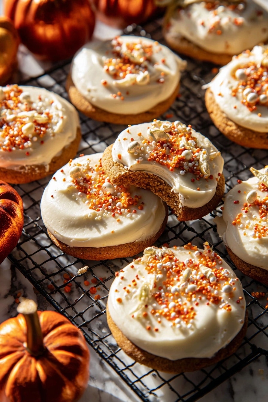 The image shows a group of round cookies, each with one thick, creamy white frosting layer on top. The frosting is smooth and spread evenly, decorated with small orange, white, and gold sprinkles scattered on the surface. One cookie is lifted slightly, showing the soft brown cookie base beneath the frosting. The cookies rest on a black wire cooling rack placed on a white marbled surface. Around the cookies, there are a few small, shiny dark orange mini pumpkins adding a warm autumn feel. Bright sunlight shines on the scene, creating strong shadows and highlighting the textures. Photo taken with an iphone --ar 2:3 --v 7 - Frosted Soft Pumpkin Sugar Cookies, pumpkin sugar cookies, soft fall cookies, pumpkin dessert recipes, easy pumpkin cookies