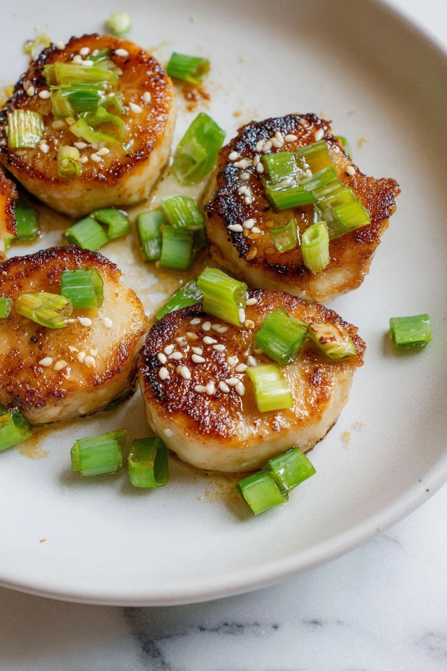 The image shows five small round pieces of golden-brown cooked food with a slightly crispy and caramelized texture on top. Each piece is garnished with small green chopped scallions and sprinkled with white sesame seeds. They are arranged on a white plate with a smooth, slightly matte surface, placed on a white marbled textured background. The food looks warm and freshly cooked, with the colors of golden brown, light green, and white creating a fresh and appetizing look. photo taken with an iphone --ar 2:3 --v 7 - Miso Soy King Oyster Mushroom, Vegan Scallops, Vegan Mushroom Recipes, Easy Vegan Seafood, Plant-Based Ocean Flavors