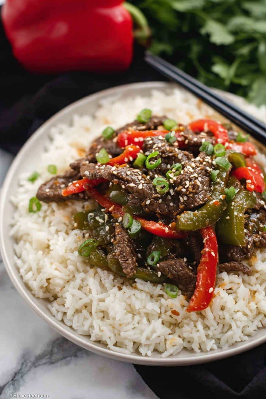 The dish shows three layers on a black plate: the bottom layer is a bed of fluffy white rice with a soft texture, the middle layer has bright green and red cooked bell peppers that look tender and shiny, and the top layer is dark brown strips of cooked beef covered with white sesame seeds and small pieces of green onion scattered on top. The background is a white marbled texture with a pair of dark chopsticks resting near the plate. photo taken with an iphone --ar 2:3 --v 7 - Crockpot Pepper Steak, easy slow cooker beef dinner, tender beef and peppers recipe, savory crockpot beef, quick comfort food dinner