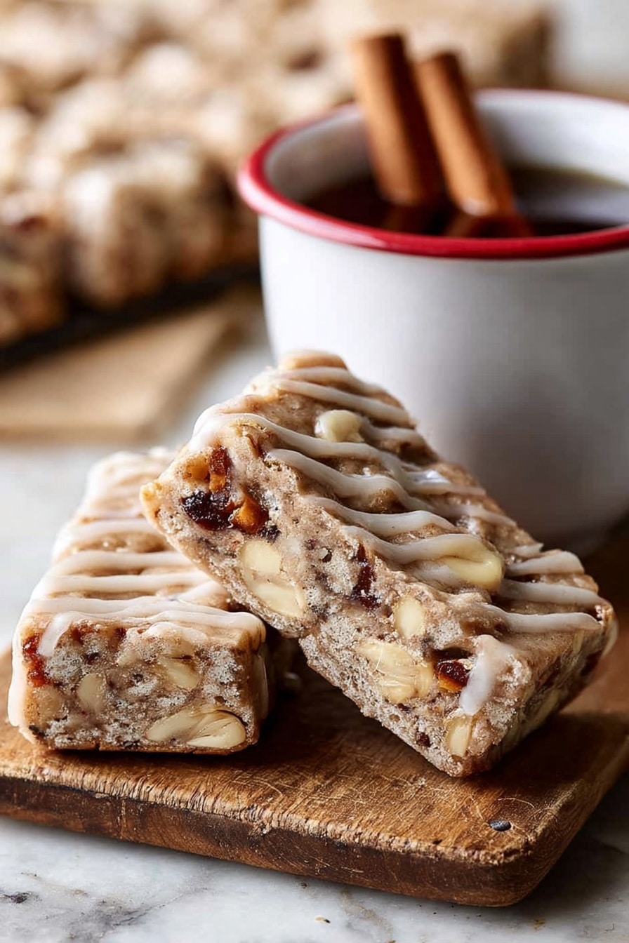 The image shows two triangular bars leaning against each other on a wooden board with a cinnamon stick nearby. Each bar has a thick, light brown base with a slightly crumbly texture, filled with visible chunks of nuts and possibly dried fruit, giving darker brown and creamy white spots inside. The bars are drizzled with a light tan glaze in thin lines across the top and sides. Next to the bars is a white cup with a red rim containing a dark liquid and two cinnamon sticks inside. The background is blurred but shows more bars on a white marbled surface. photo taken with an iphone --ar 2:3 --v 7 - Brown Butter Apple Blondies with Cinnamon Maple Glaze, fall dessert recipes, cozy apple blondies, cinnamon maple glaze treat, easy autumn blondies