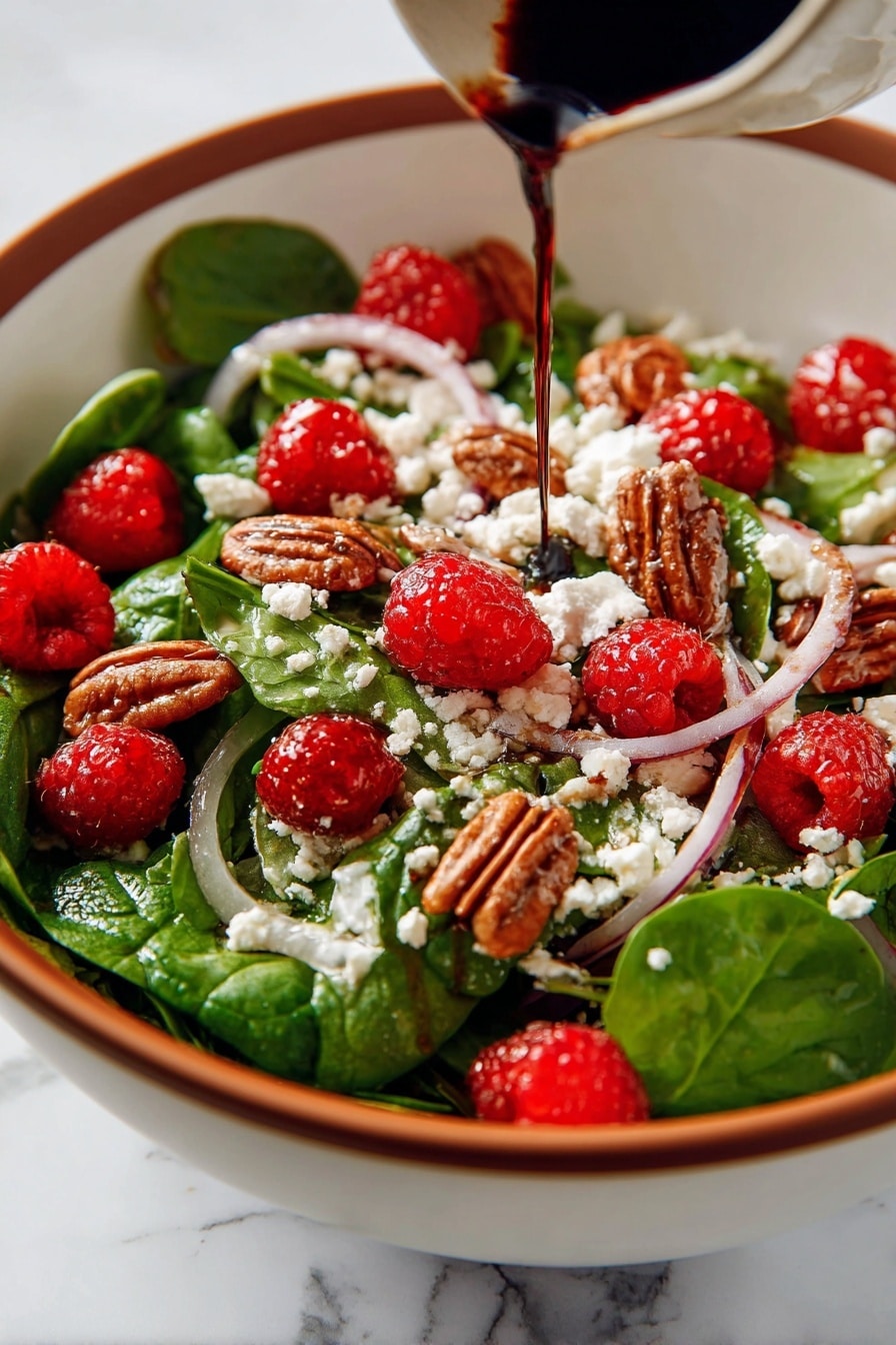 This image shows a fresh salad in a white bowl with a wooden spoon on the side. The salad has several layers and colors: the base is bright green spinach leaves mixed with thin slices of purple onion; scattered on top are red raspberries and brown pecan nuts adding texture; white crumbled goat cheese is spread evenly across the salad, with dark balsamic glaze drizzled over everything, giving a shiny and rich look. The bowl rests on a blue cloth, all placed on a white marbled surface. Photo taken with an iphone --ar 2:3 --v 7 - Spinach Salad with Goat Cheese Raspberries and Toasted Pecans, healthy spinach salad with goat cheese and berries, quick gourmet spinach salad recipe, fresh berry and pecan salad, easy spinach salad with cheese and nuts