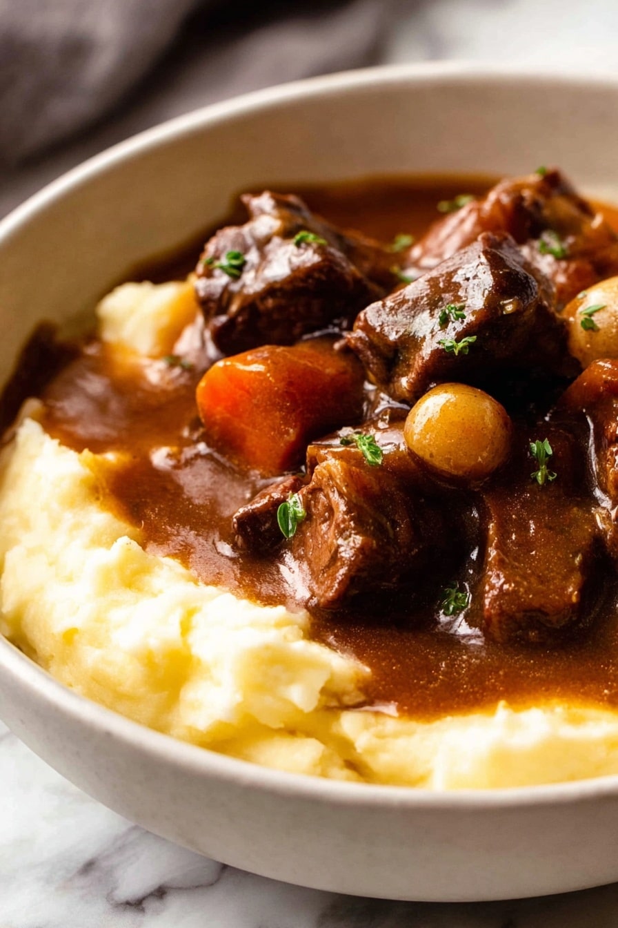 A white bowl filled with two layers: the bottom layer is smooth, creamy mashed potatoes in a light yellow color, and the top layer is a rich, dark brown stew with chunks of tender meat, whole small onions, and thick slices of carrots, all coated in a shiny gravy. The stew slightly spills over the mashed potatoes, garnished with small sprinkles of green herbs. The bowl is placed on a white marbled surface with a folded cloth and a glass of red wine slightly visible in the background along with a detailed old-fashioned spoon in front of the bowl. Photo taken with an iphone --ar 2:3 --v 7 - Beef Bourguignon, Beef Burgundy, classic French stew, beef slow cooker recipe, French beef stew