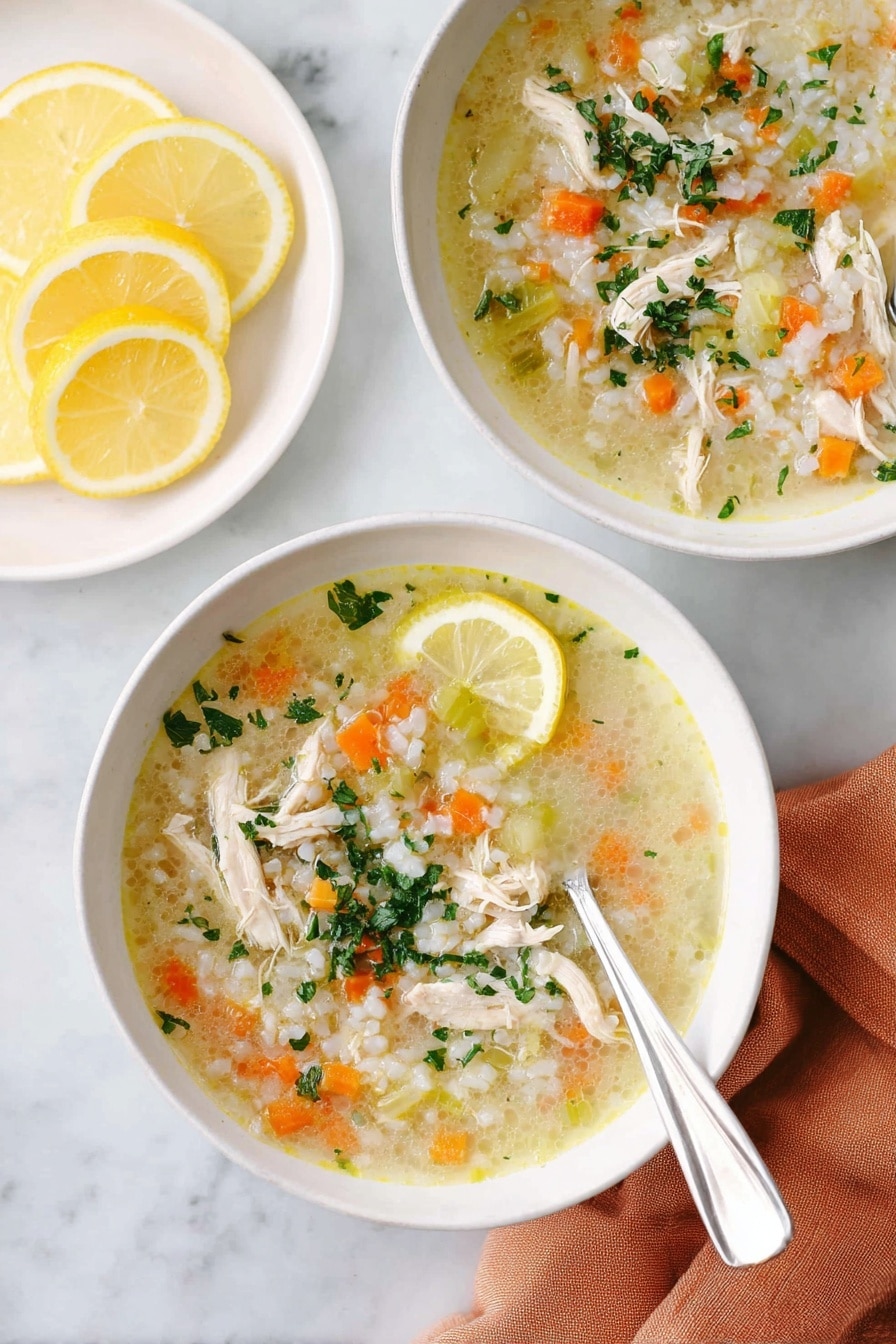 Two white bowls filled with chicken soup placed on a white marbled surface. Each bowl has a light yellow broth with shredded chicken pieces, small diced orange carrots, small green celery pieces, and white rice, topped with chopped green herbs. One bowl shows a silver spoon resting inside the bowl on the right side. A lemon wedge sits on the edge of the front bowl. Next to the bowls, there is a white plate holding several lemon slices. A soft orange cloth napkin lies under the front bowl. Photo taken with an iphone --ar 2:3 --v 7 - Lemon Chicken Rice Soup, healthy chicken soup with lemon, easy lemon chicken soup, comforting rice soup, quick lemon chicken dinner