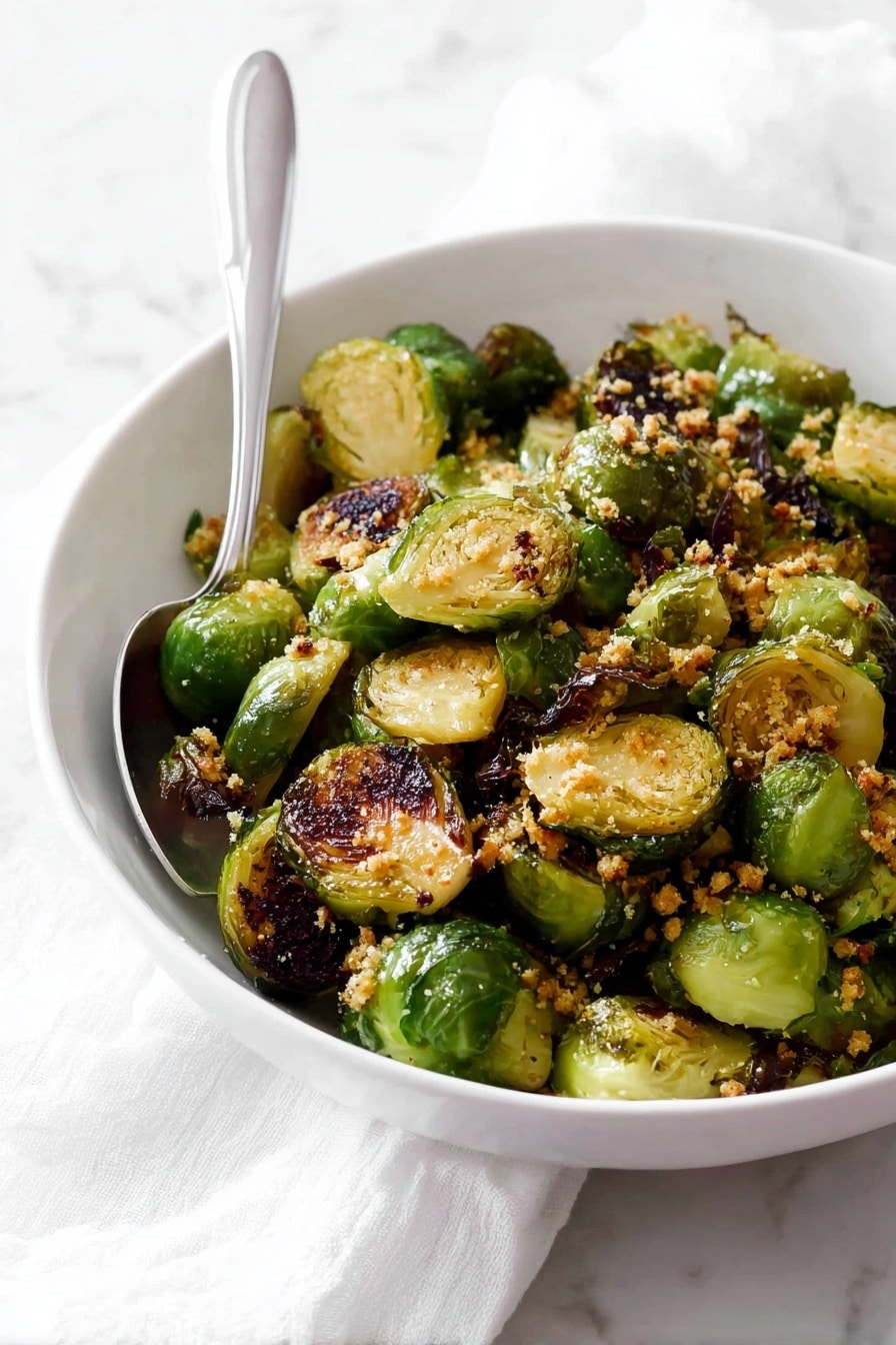 A white bowl filled with two layers of roasted Brussels sprouts, each piece halved to show a mix of light green interiors and crispy dark brown charred edges, giving a textured look; sprinkled with small bits of golden-brown garlic or breadcrumbs on top, a silver spoon placed inside the bowl rests against the side; the bowl is set on a white marbled surface with a white cloth nearby, creating a simple, clean setting. photo taken with an iphone --ar 2:3 --v 7 - Garlic Butter Brussels Sprouts, Roasted Brussels Sprouts with Garlic and Honey, Easy Brussels Sprouts Side Dish, Crispy Brussels Sprouts Recipe, Healthy Brussels Sprouts