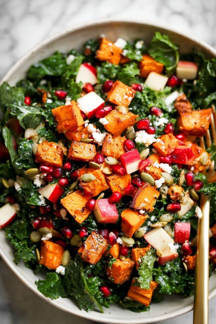 The image shows a colorful salad in a white bowl on a white marbled surface. The salad has four main layers: dark green kale leaves forming the base layer, orange roasted sweet potato cubes scattered evenly on top, red and white chopped apple pieces mixed throughout, and small bright red pomegranate seeds sprinkled around. There are also small white crumbles of cheese and light brown pumpkin seeds spread over the salad, adding texture. A gold fork rests inside the bowl, partially hidden by the salad. The photo taken with an iphone --ar 2:3 --v 7 - Fall Butternut Squash Apple Salad, autumn squash apple salad, seasonal fall salad with butternut squash, healthy fall salad recipes, easy autumn vegetable salad