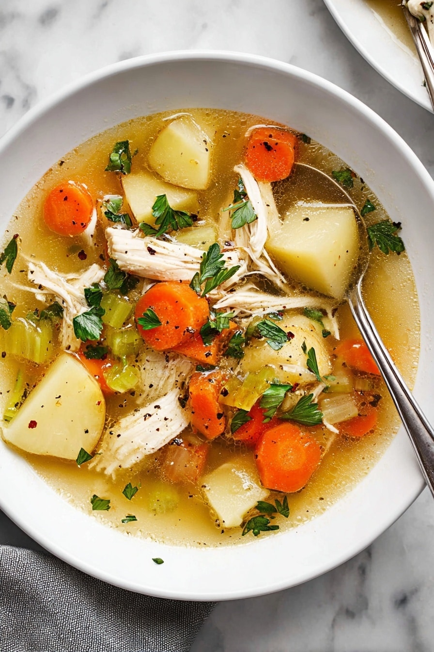 The image shows a white plate filled with clear chicken soup that has a golden broth base. Inside the soup, there are several layers: large pieces of white shredded chicken, sliced orange carrots, light beige potato slices, and sections of green celery. Scattered on top are fresh green parsley leaves and small black pepper bits. A silver spoon is partially dipped into the soup on the right side of the plate, resting against the edge. The plate is placed on a white marbled surface, with a grey cloth partially visible at the bottom left corner. photo taken with an iphone --ar 2:3 --v 7 - Ultimate Chicken Soup, comforting chicken soup, healthy chicken soup, hearty chicken vegetable soup, easy homemade chicken soup