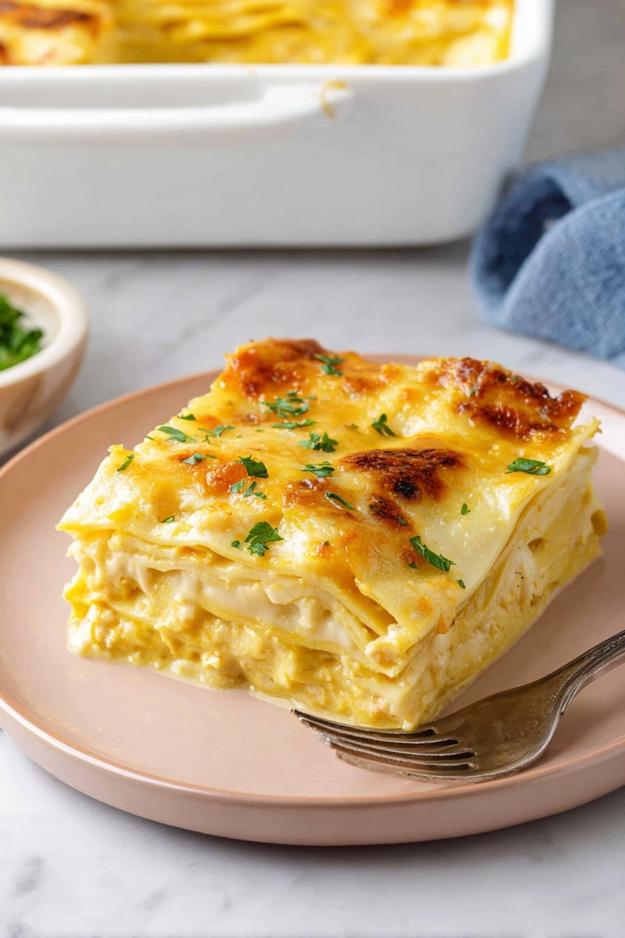 A square piece of lasagna with three visible layers is placed on a pale pink plate on a white marbled surface. The top layer is covered with melted golden-yellow cheese, sprinkled with fresh green herbs. Beneath, you can see creamy yellow sauce mixed with soft white pasta sheets and some herbs. In the background, a white baking dish with a golden top edge of more lasagna and a silver fork resting on the plate accompany the serving. photo taken with an iphone --ar 2:3 --v 7 - Butternut Squash Lasagna, vegetarian butternut squash lasagna, healthy butternut squash lasagna, creamy squash lasagna, fall comfort food lasagna