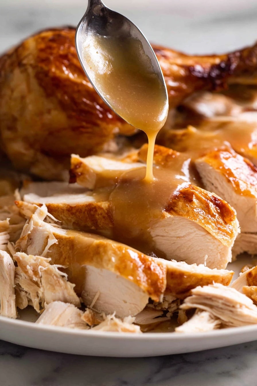 A white plate is filled with sliced roasted chicken with a shiny, golden-brown skin. The chicken is cut into thick pieces, showing tender, white meat inside. At the center, smooth brown gravy is being poured from a spoon, slowly flowing over the chicken slices, adding a glossy layer. Some shredded chicken pieces with light beige tones are placed around the sliced chicken, creating a mix of textures. In the background, part of a roasted chicken drumstick with crispy skin is visible. The entire scene is set on a white marbled surface. Photo taken with an iphone --ar 2:3 --v 7 - KFC-Style Homemade Gravy, quick homemade gravy, easy gravy recipe, homemade gravy tips, rich flavorful gravy