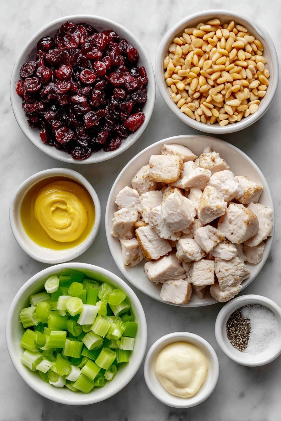 Flat lay of cooked chicken breast chopped into bite-sized pieces, a sliced celery stalk with bright green ribs, thinly sliced green onions showing white and green sections, a small white bowl filled with glossy sweet dried cranberries, a small white bowl containing toasted golden pine nuts, a small white bowl of creamy pale mayonnaise, a small white bowl holding smooth Dijon mustard, a small white bowl with coarse salt crystals, and a small white bowl with freshly ground black pepper placed on a clean white marble surface, soft natural light, photo taken with an iPhone, professional food photography style, fresh ingredients, white ceramic bowls, no bottles, no duplicates, no utensils, no packaging --ar 2:3 --v 7 --p awthu7i m7354615311229779997 - Cranberry Chicken Salad, cranberry chicken salad recipe, healthy chicken salad with cranberries, easy chicken salad with cranberries, fruit chicken salad recipe