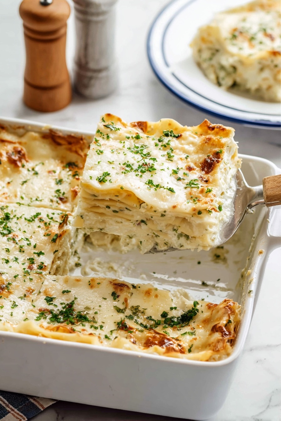 The image shows a white baking dish filled with a six-layer lasagna. Each layer consists of creamy white sauce and pasta sheets with soft, textured edges. The top layer is covered with melted white cheese sprinkled with finely chopped green herbs. The lasagna has a golden-brown crust on some edges. A metal spatula with a wooden handle is placed inside the dish, lifting one square piece from the corner. In the background, a slice of lasagna sits on a white plate with blue trim on a white marbled surface, with a blurred salt and pepper shaker set partly visible. Photo taken with an iphone --ar 2:3 --v 7 - Creamy Chicken Boursin Lasagna, Boursin Cheese Lasagna, Chicken Lasagna with Boursin, Gourmet Chicken Lasagna, Easy Creamy Lasagna