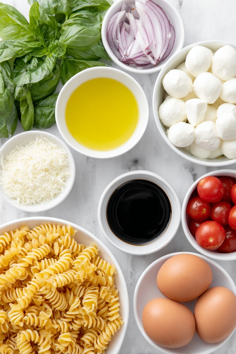 Flat lay of cavatappi pasta twisted spirals, a small white bowl of extra-virgin olive oil glistening, a small white bowl of fresh lemon juice pale yellow, a small white bowl of dark balsamic vinegar, a small white bowl of finely grated pecorino cheese light off-white, a few garlic cloves whole and peeled, a small pile of coarse sea salt crystals, a few twists of freshly ground black pepper, a handful of halved bright red cherry tomatoes, several halved mini mozzarella balls pure white and smooth, thinly sliced rings of red onion vibrant purple, a heaping handful of fresh basil leaves deep green torn and whole, several whole brown eggs with clean shells placed nearby, all arranged symmetrically on simple white ceramic bowls and plates, placed on a clean white marble surface, soft natural light, photo taken with an iPhone, professional food photography style, fresh ingredients, white ceramic bowls, no bottles, no duplicates, no utensils, no packaging --ar 2:3 --v 7 --p m7354615311229779997 - Caprese Pasta Salad with Cherry Tomatoes, summer pasta salad, easy Caprese pasta, fresh cherry tomato salad, Italian pasta salad