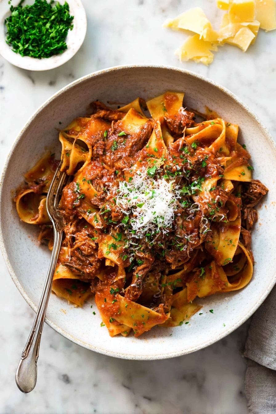 A bowl filled with wide, soft pasta noodles layered with shredded brown meat mixed in a thick red tomato sauce. The pasta sits in a white bowl, topped with a small pile of grated light cheese and finely chopped green herbs. A fork is placed inside the bowl, resting on the pasta. The background shows a white marbled surface with a small white dish holding chopped green herbs and pieces of yellow cheese scattered nearby. Photo taken with an iphone --ar 2:3 --v 7 - Slow Cooker Beef Ragu Pasta, Beef Ragu, Slow Cooker Recipes, Comforting Pasta Dishes, Easy Beef Pasta
