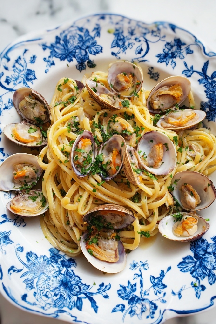 A white plate with blue floral patterns holds a serving of spaghetti pasta as the bottom layer, light yellow and slightly shiny. On top of the pasta, there are many open clam shells with light brown and white inner textures and soft orange clam meat inside. The dish is sprinkled with finely chopped green parsley evenly over the pasta and clams. The plate is placed on a white marbled surface. photo taken with an iphone --ar 2:3 --v 7 - Linguine with Clams, seafood pasta recipes, Italian clam linguine, quick clam pasta, easy seafood dinner