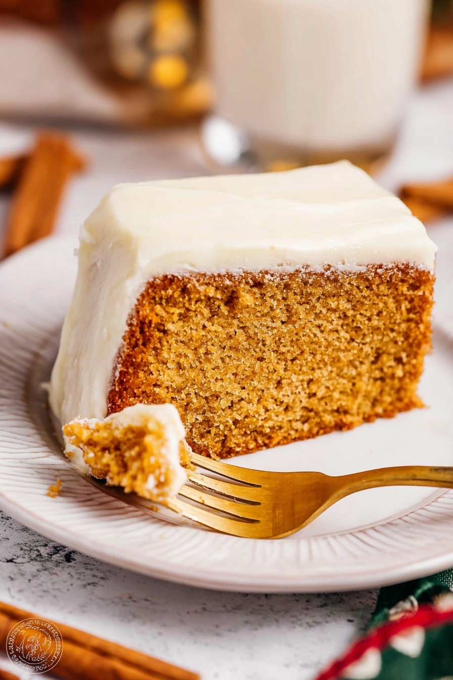The image shows a slice of thick, light brown cake with a moist texture, topped with a thick white frosting layer covering the top and sides. The slice is placed on a white plate with a subtle embossed design along the edge. A golden fork is cutting into the cake slice. The background has a white marbled texture with blurred elements including cinnamon sticks and a glass cup. Warm lighting highlights the soft texture of the frosting and the crumb of the cake. Photo taken with an iphone --ar 2:3 --v 7 - Eggnog Bread with Spiced Glaze, festive eggnog bread, holiday bread recipes, spiced holiday bread, moist eggnog loaf
