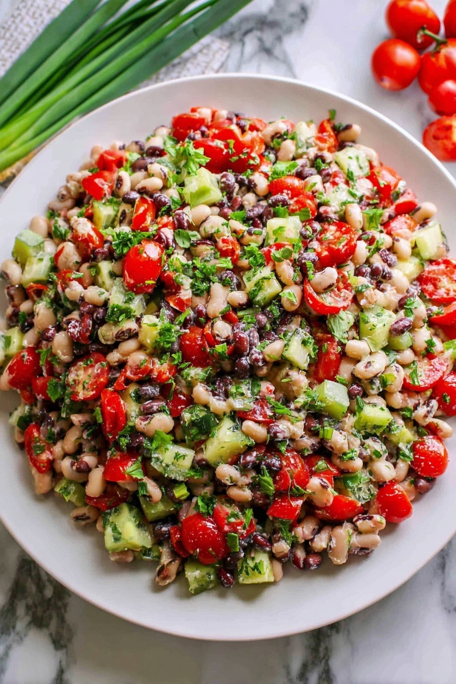 A large white plate holds a mixed bean salad piled high with many colorful ingredients. The salad has three main layers visible: the base layer is made of small, round white and black beans mixed closely together, the middle layer is scattered chopped bright red cherry tomatoes and green cucumber pieces, and the top layer is sprinkled with chopped fresh green herbs that add a fresh, leafy texture. The salad looks fresh and slightly glossy, suggesting a light dressing. The plate sits on a white marbled surface, with green onions and red cherry tomatoes placed nearby for decoration. photo taken with an iphone --ar 2:3 --v 7 - Mediterranean Bean Salad with Feta, healthy bean salad, quick Mediterranean salad, protein-packed vegetarian salad, easy feta bean salad