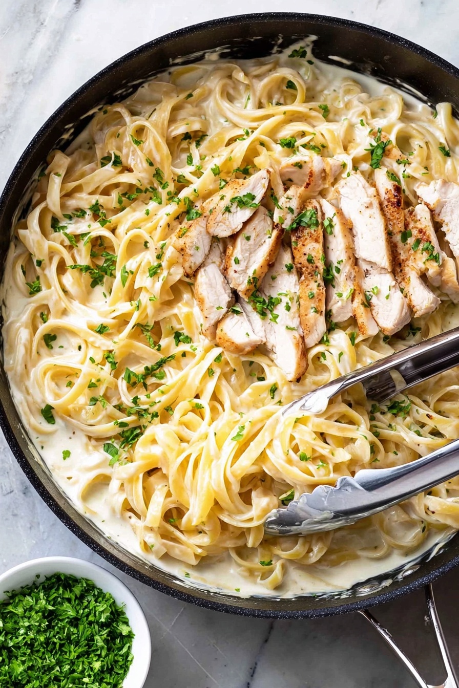 The image shows a black pan filled with creamy white sauce mixed with long, light yellow fettuccine noodles. On top of the noodles, there are several thin slices of cooked white meat with light brown edges. Small green parsley pieces are sprinkled all over the dish, adding a fresh touch. A pair of metal tongs rests inside the pan, slightly lifting some of the noodles. The pan is placed on a white marbled surface, and next to it is a small white bowl containing finely chopped green herbs. Photo taken with an iphone --ar 2:3 --v 7 - One-Pot Chicken Alfredo, creamy chicken pasta, easy weeknight dinner, quick Alfredo recipe, chicken pasta skillet