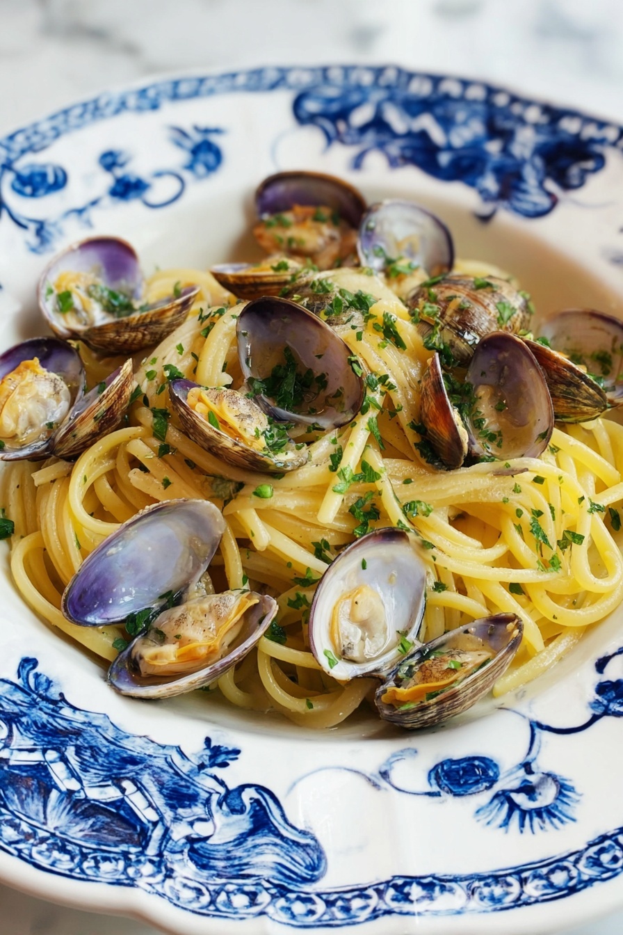 A white plate with blue floral patterns holds a serving of spaghetti pasta layered at the bottom, showing a pale yellow color and smooth texture. Scattered over the pasta are many opened clam shells, beige and light brown with tender clam meat inside, slightly orange and shiny. Fresh chopped green herbs are sprinkled over the clams and pasta, adding a bright touch. The plate rests on a white marbled surface. photo taken with an iphone --ar 2:3 --v 7 - Linguine with Clams, seafood pasta recipes, Italian clam linguine, quick clam pasta, easy seafood dinner