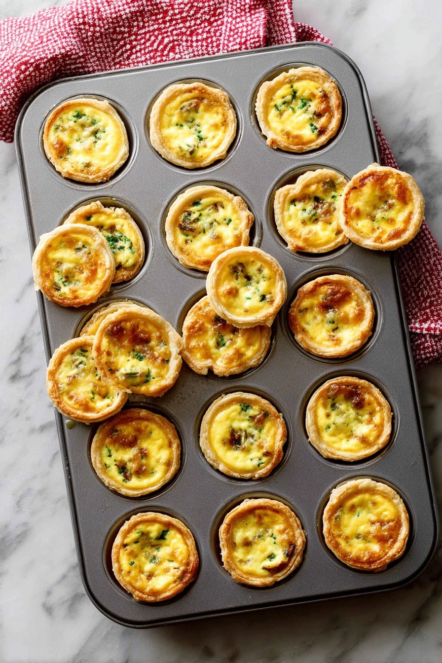 A gray metal muffin tray filled with 24 mini egg tarts, each tart consisting of a golden brown crust that forms a cup holding a smooth, creamy yellow egg filling mixed with small green and brown bits of vegetables or meat. Some tarts are slightly raised above the tray’s edge, showing a crisp outer layer, while a few are tilted or removed, revealing their round, flaky textured bottoms. The tray rests on a white marbled surface with a red and white checkered towel partly visible at the top left corner. Photo taken with an iphone --ar 2:3 --v 7 - Mini Quiche Recipe, flaky pie crust mini quiches, savory bite-sized breakfast, easy quiche for brunch, customizable mini pies