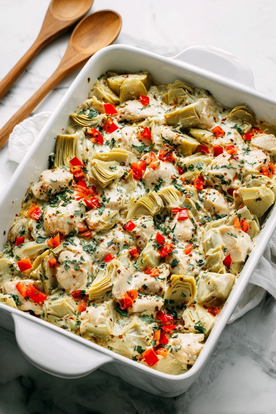 A white rectangular baking dish filled with a layered mix of creamy white sauce, pieces of light beige cooked chicken, and quartered pale green artichoke hearts. The dish is sprinkled with small, bright red bell pepper pieces and finely chopped dark green herbs, creating a colorful contrast. The textures range from creamy sauce to tender chunks of chicken and soft artichokes, all blended evenly across the dish. The dish sits on a white marbled surface with two wooden spoons with white handles placed behind it. Photo taken with an iphone --ar 2:3 --v 7 - Spinach Artichoke Chicken Bake, healthy chicken casserole, easy weeknight dinner, baked chicken with spinach and artichokes, creamy garlic chicken