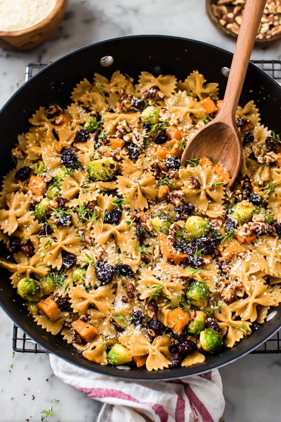A large black pot filled with a colorful mix of farfalle pasta and small pieces of roasted orange sweet potatoes spread all over. Bright green Brussels sprouts cut in halves and small dark purple dried berries are scattered inside. There are bits of chopped pecans and a light sprinkle of grated cheese on top, with little green herb leaves spread around. In the pot, a wooden spoon rests on the food, and the scene is set on a white marbled surface, with some pecans and a small bowl of grated cheese nearby. A white cloth with a red stripe is partially visible next to the pot. Photo taken with an iphone --ar 2:3 --v 7 - Brussels Sprouts Pasta with Brown Butter, Brussels Sprouts Pasta, Brown Butter Pasta, Fall Vegetable Pasta, Easy Brussels Sprouts Recipe