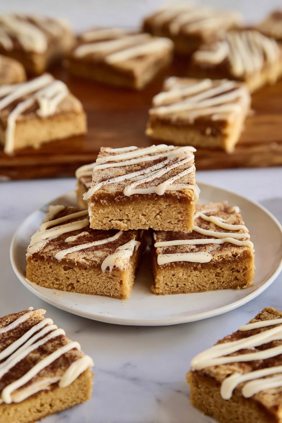The image shows several square-shaped blondies with two visible layers: a thick golden-brown base with a soft texture and a darker cinnamon-brown sugar layer on top, sprinkled with a thin drizzle of creamy white icing forming diagonal lines. Three blondies are stacked in the center of a white plate, with more pieces spread around on the same plate and on a wooden board in the background, all placed on a white marbled surface. photo taken with an iphone --ar 2:3 --v 7 - Cinnamon Sugar Blondies with Cinnamon Glaze, cinnamon blondie bars, easy cinnamon dessert, buttery cinnamon bars, cinnamon glaze blondies