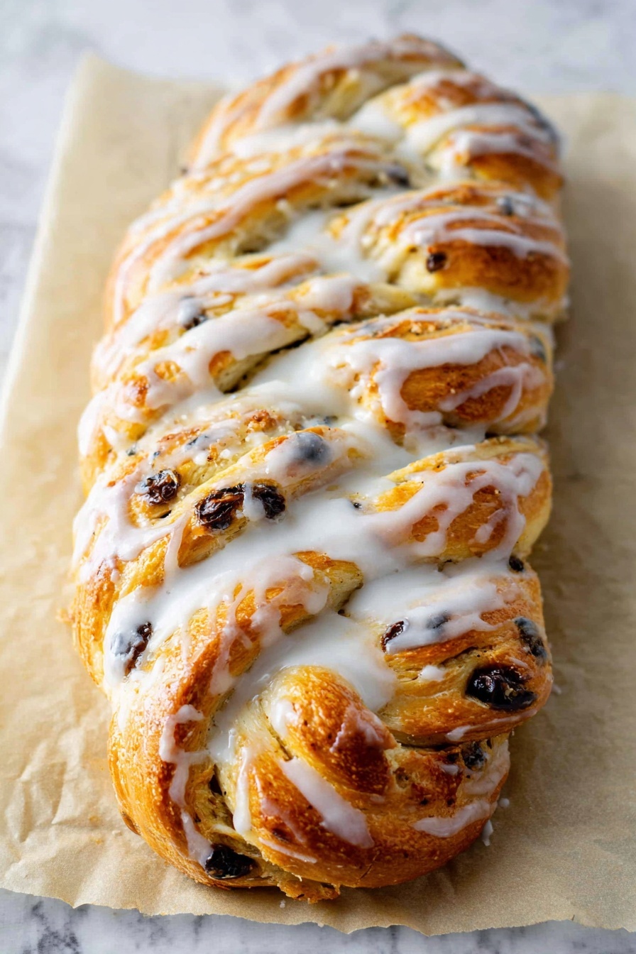 A golden brown braided bread loaf is placed on a sheet of parchment paper on a white marbled surface. The bread has multiple visible layers formed by the braid, with bits of dark raisins or chocolate chips scattered throughout the dough. A thick, white glaze is drizzled generously and unevenly over the top, pooling slightly in the crevices and along the edges, giving it a shiny, slightly wet look. The texture of the bread appears soft and fluffy with a slightly crisp crust on top. Photo taken with an iphone --ar 2:3 --v 7 - German Stollen Bread, traditional holiday bread, festive German cake, Christmas stollen recipe, homemade Stollen bread