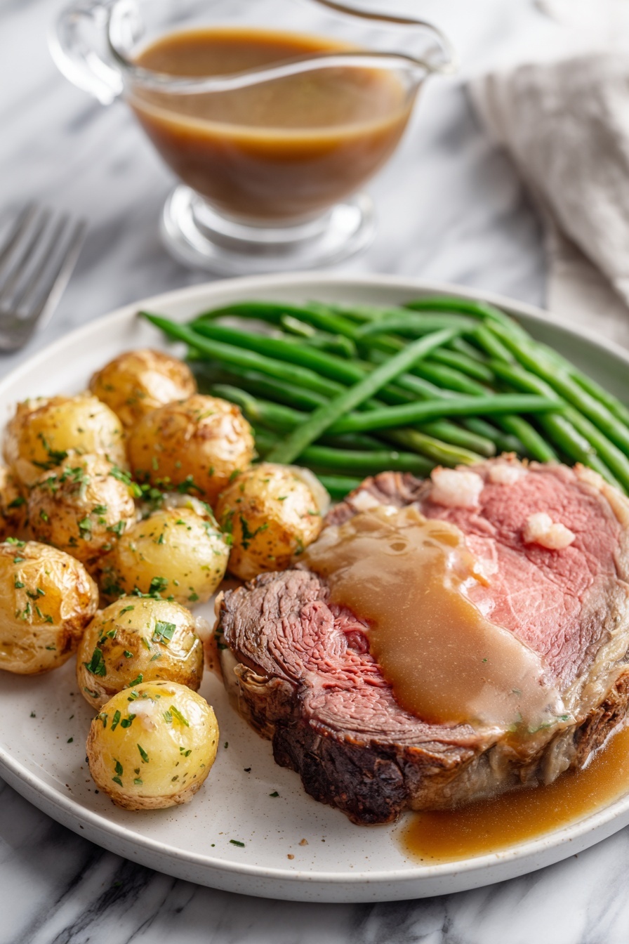A white plate on a white marbled surface holds a meal with three main parts: a thick, medium-rare roast beef slice with a pink center and browned edges, topped with brown gravy that also pools around it; next to it, a pile of roasted small potatoes with golden brown skins sprinkled with green herbs; and a bunch of bright green cooked green beans laid neatly beside the potatoes. In the background, there is a clear glass gravy boat filled with brown gravy on the white marbled surface. photo taken with an iphone --ar 2:3 --v 7 - Garlic Herb Butter Prime Rib, prime rib roast recipe, garlic herb beef, juicy prime rib, flavorful roast dinner