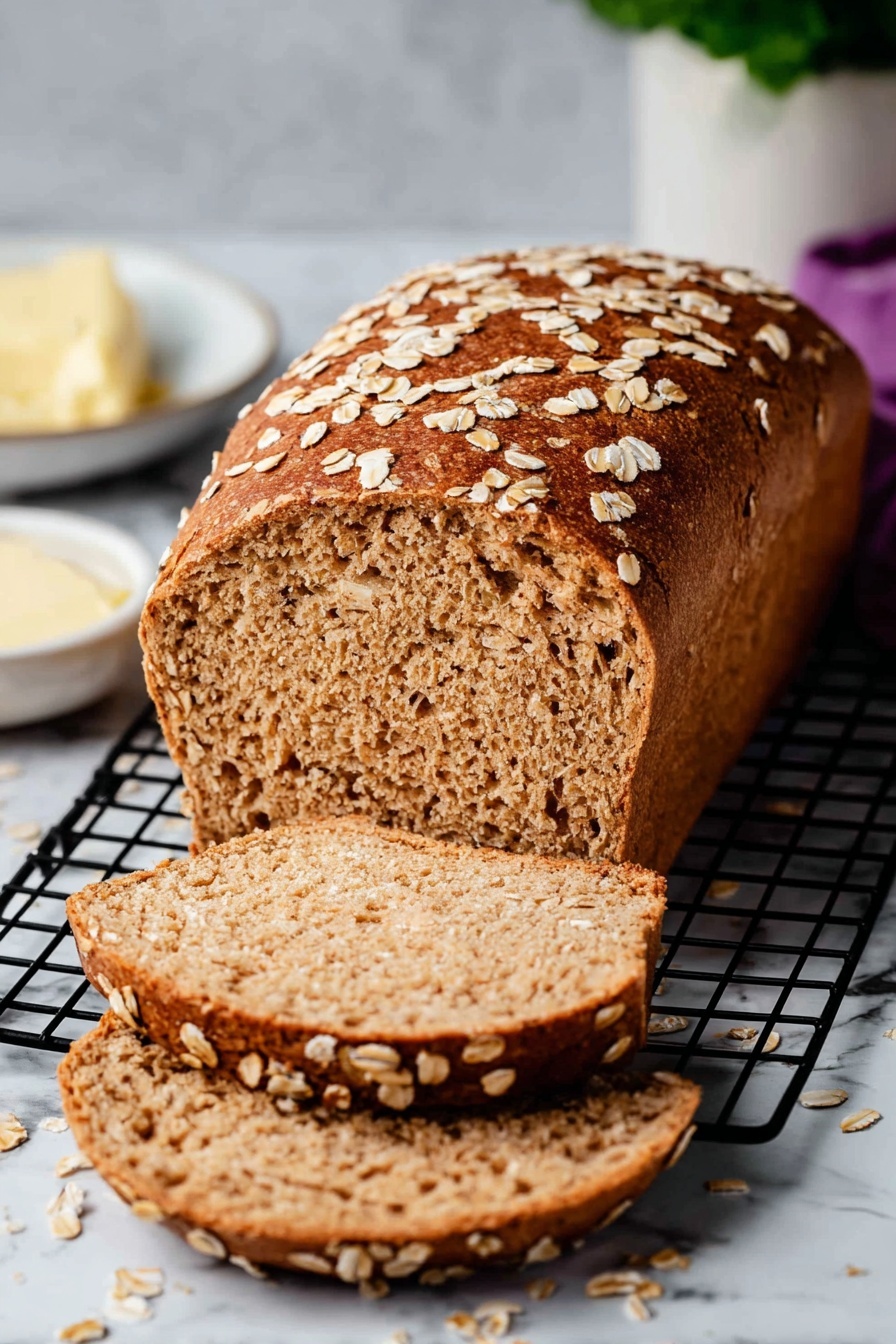 A loaf of brown bread topped with scattered oats sits on a black wire cooling rack over a white marbled surface. The loaf is partially sliced, showing two thick slices lying flat with a soft, slightly porous texture inside. The crust is a rich golden brown with more oats sprinkled on the edges of the slices. In the background, there is a small white dish with light yellow butter and a white container with a plant nearby. photo taken with an iphone --ar 2:3 --v 7 - Whole Wheat Bread, healthy homemade bread, soft whole wheat loaf, easy bread baking, nutritious bread recipe